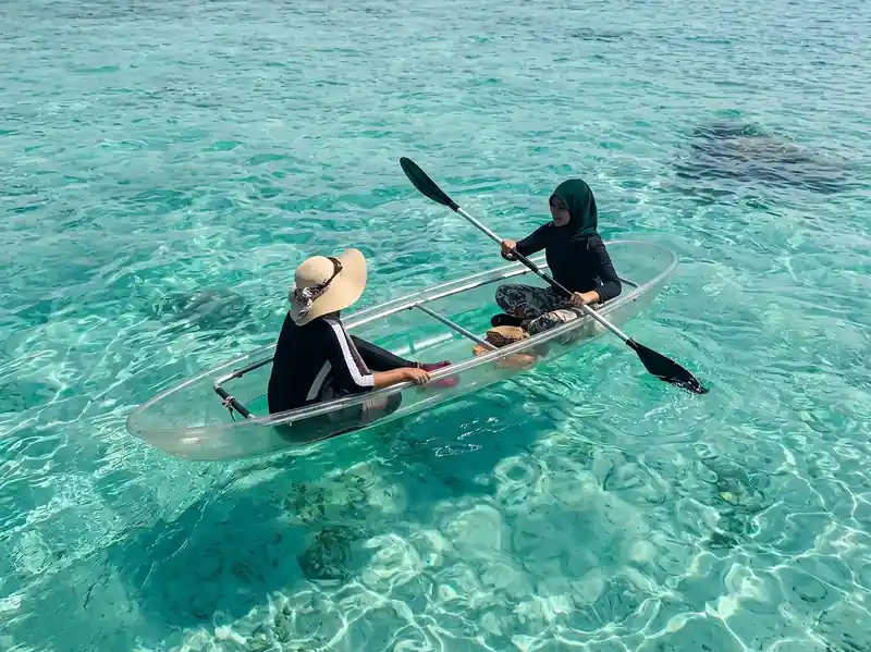 Enjoying a transparent kayak ride through crystal clear waters with Tampi Tampi Resort in the Celebes Sea